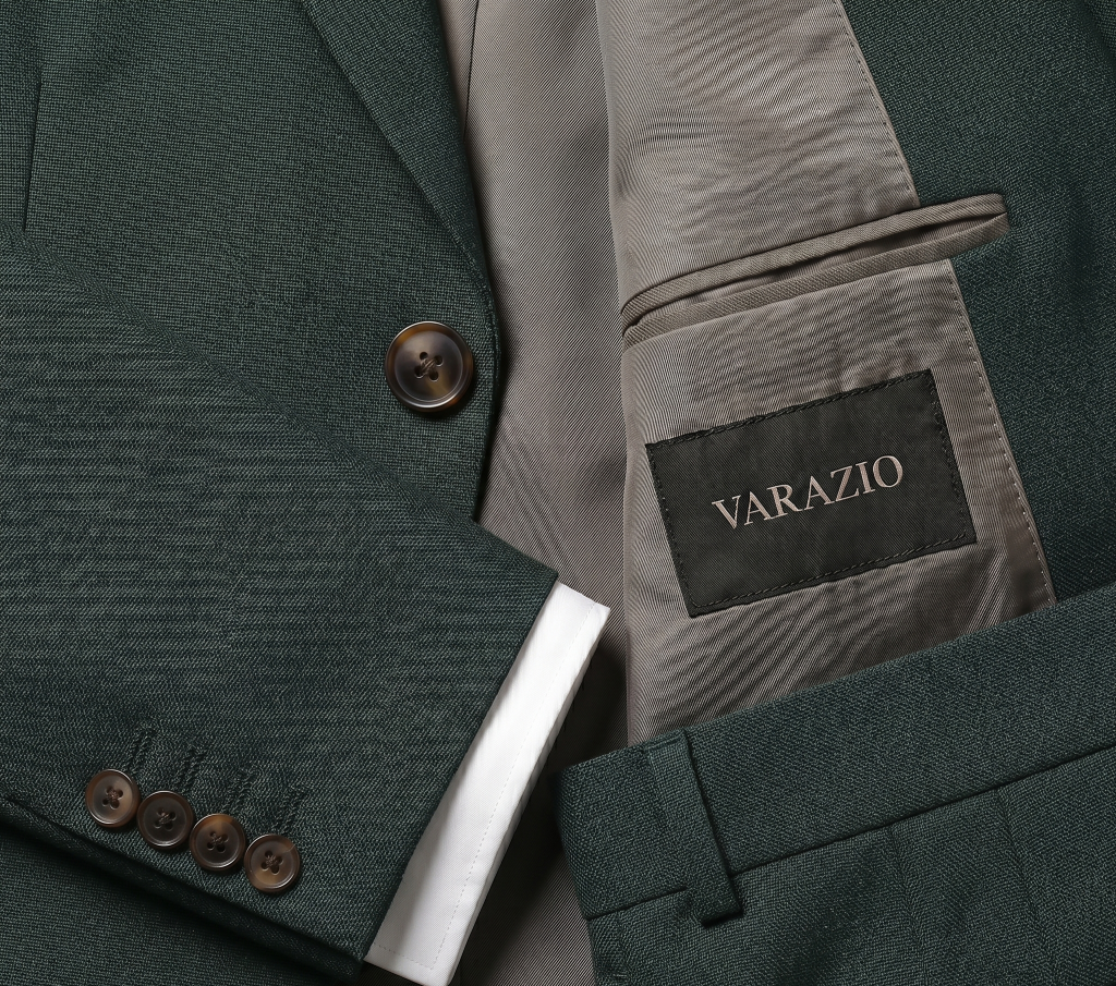Nahaufnahme einer grünen Anzugsjacke mit braunen Knöpfen und einem Innenetikett mit der Aufschrift VARAZIO.